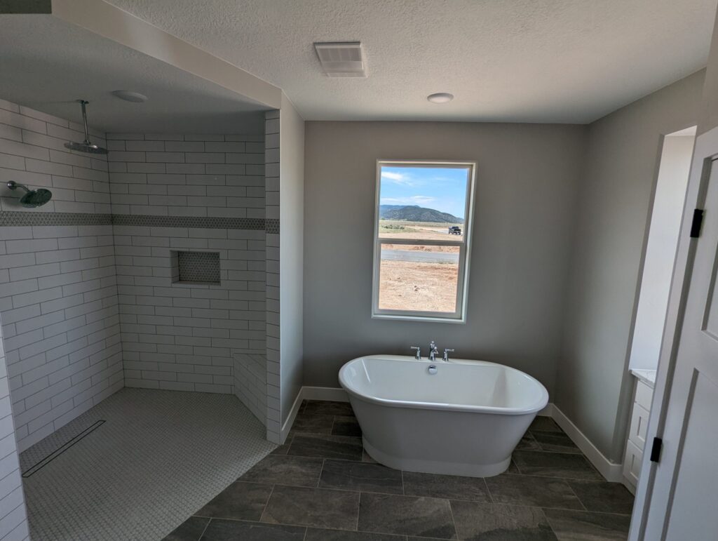 Modern bathroom interior with tiled shower, bathtub, and window view