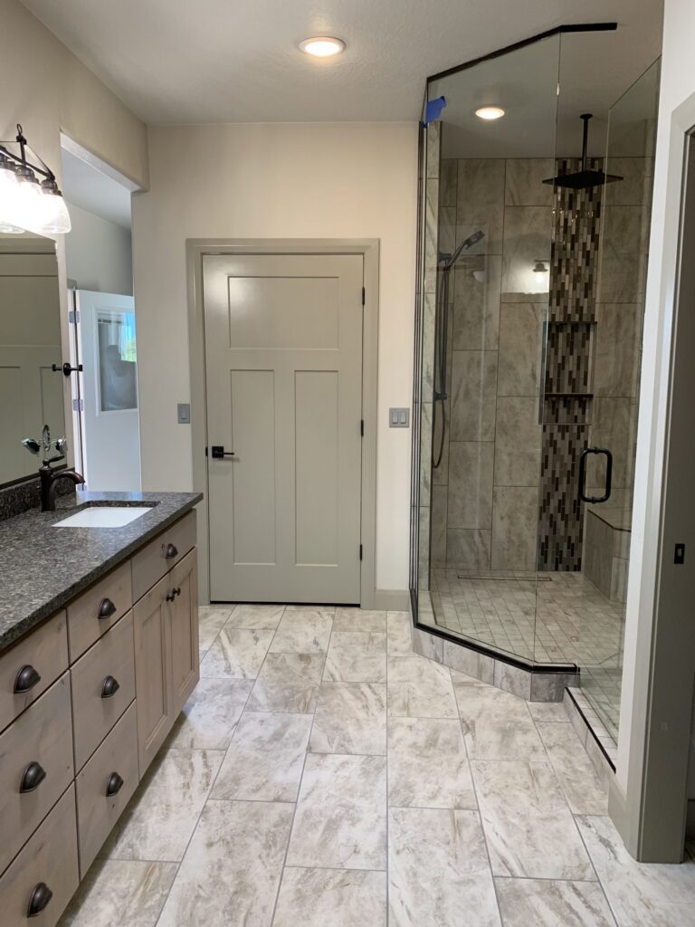 Modern bathroom remodel by Sideone Exteriors with walk-in glass shower, tile floors, and vanity