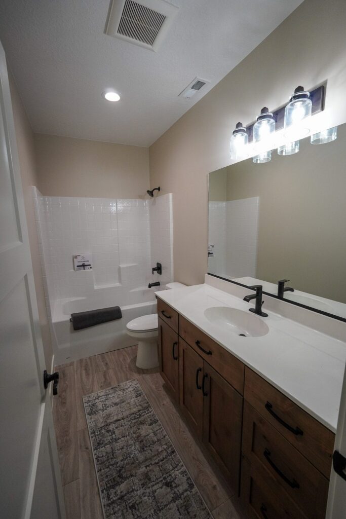 Modern bathroom with vanity, double sinks, bathtub, and ceiling lighting