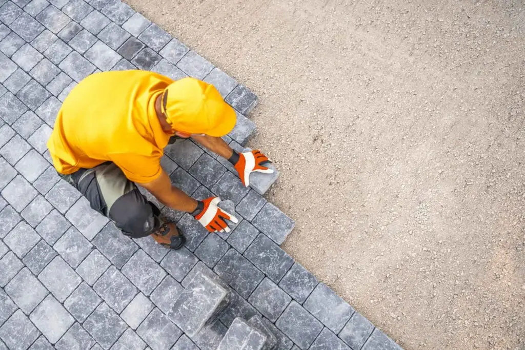 Precision Landscaping and Lawncare LLC worker installing gray pavers for a walkway