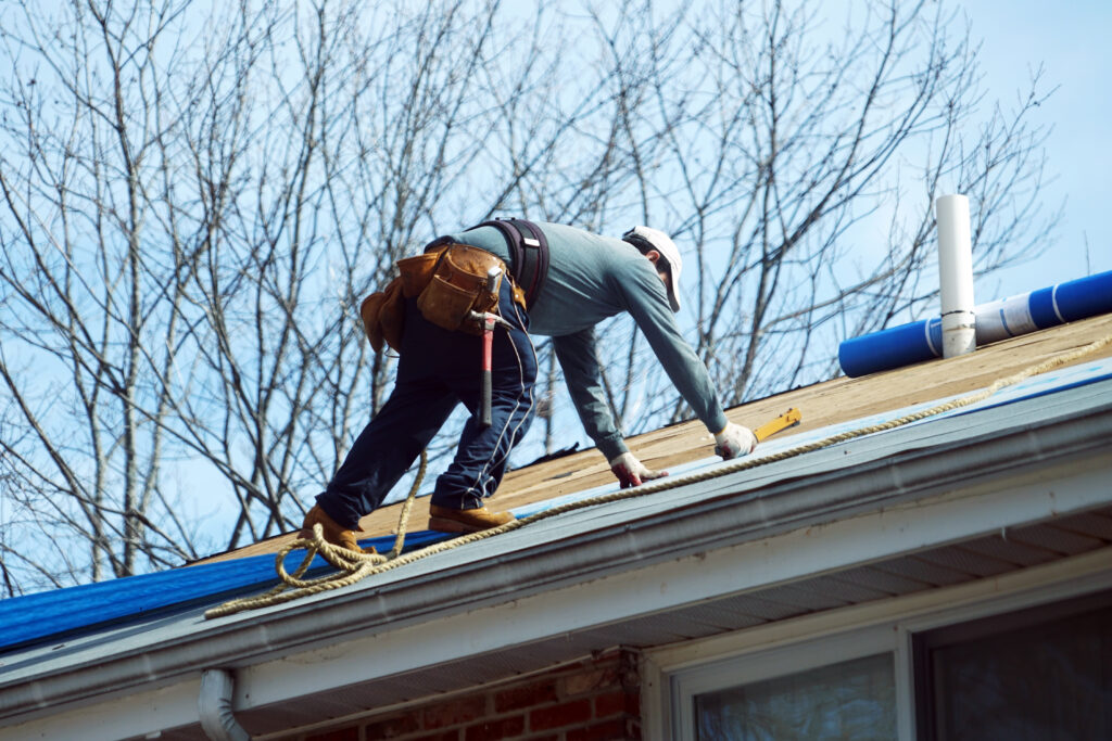 A skilled roofer installing new roofing materials on a residential home, ensuring a watertight seal and a long-lasting roof.