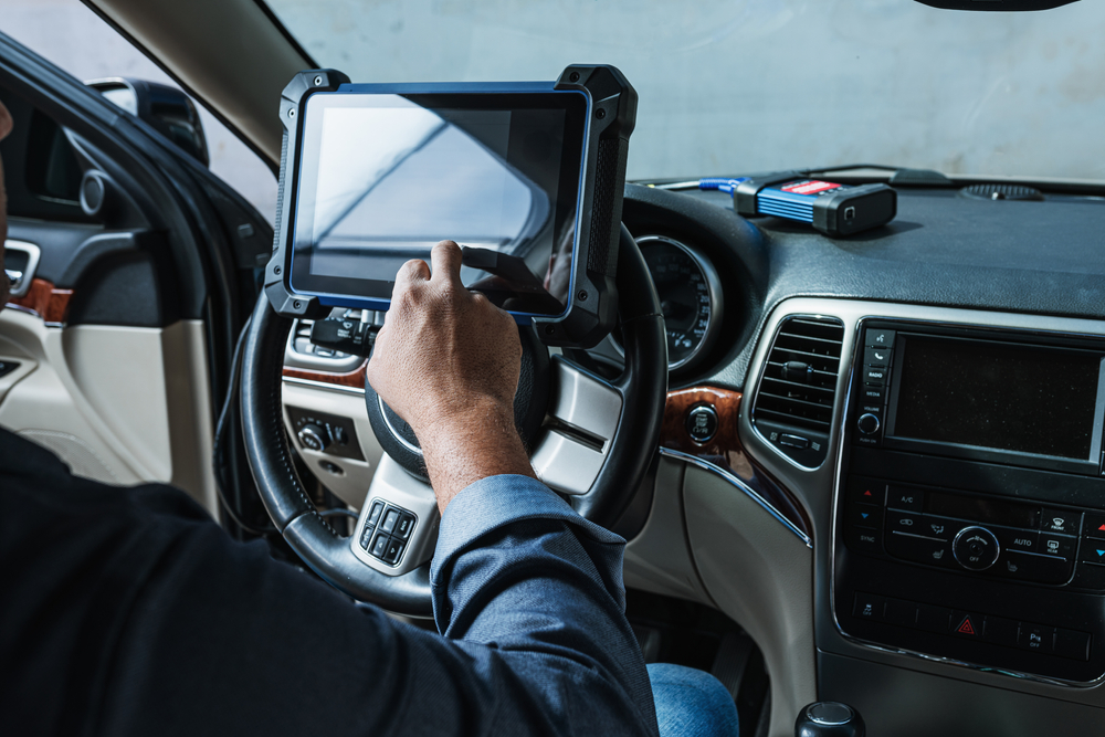 C & A Automotive technician using diagnostic tablet inside a vehicle cockpit