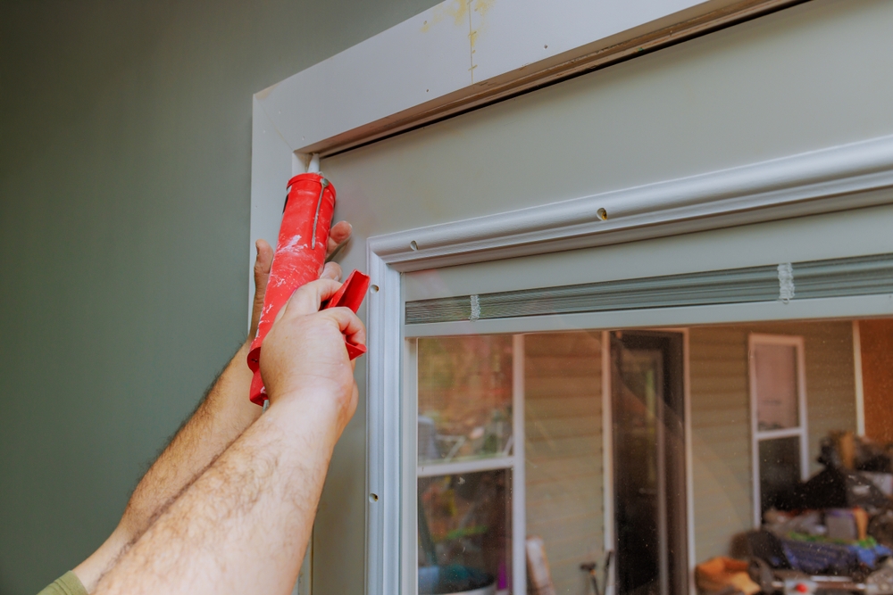 Modern Remodeling worker sealing a window frame with caulk during home renovation