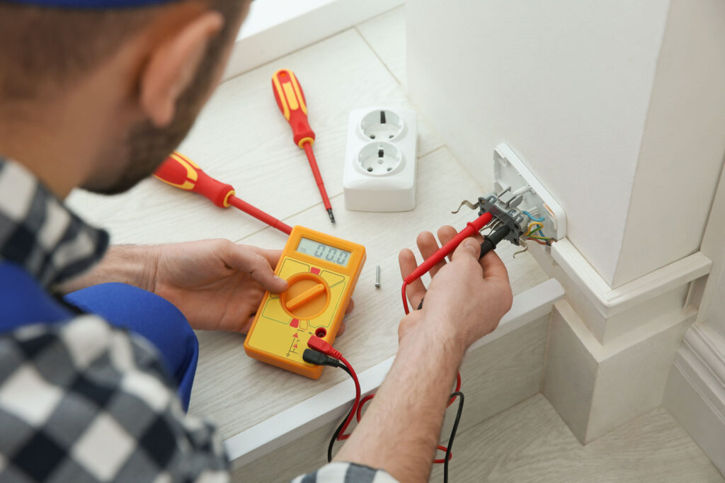 Electrician with tester checking voltage indoors