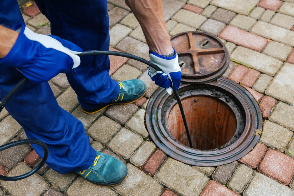 Best Jet Septic technician using vacuum hose to clean a sewer manhole