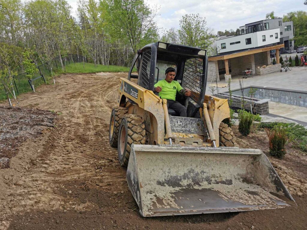 Worker levels the land for landscaping project