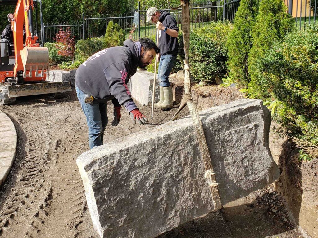 Armor Stone - men work on placing armor stone in landscaping