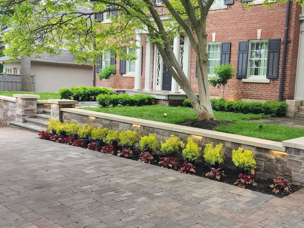 Stone Kings Landscaping front yard with manicured lawn, stone edging, and landscaped flower beds in front of a brick home