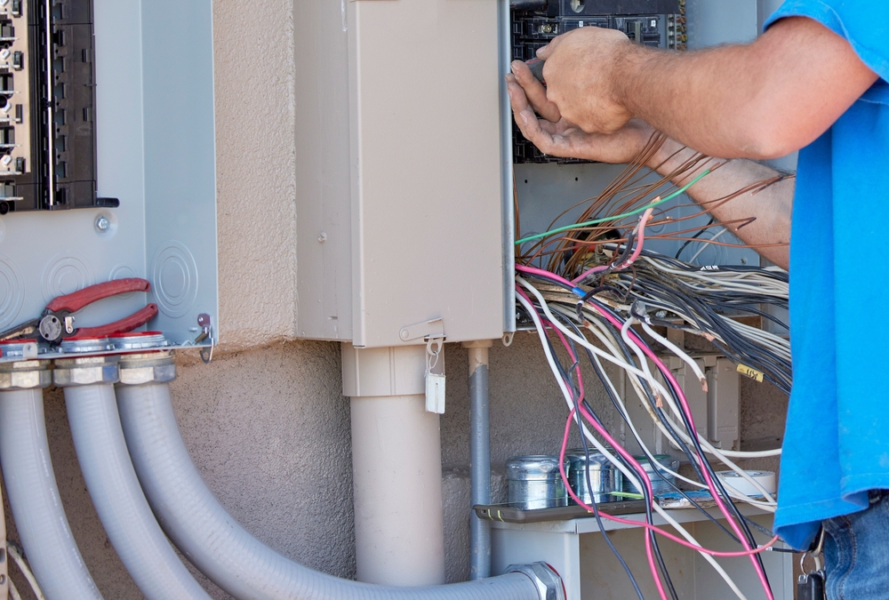 Electrician from Light Of This World Electric working on an electrical panel and wiring near a breaker box