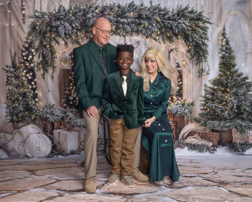 Stephanie's Musique holiday photo of a family posing in front of a decorated Christmas tree and winter backdrop
