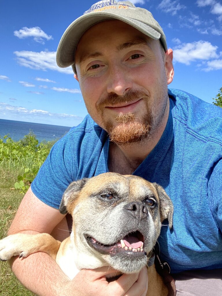 Stephanie's Musique founder smiling outdoors while holding a dog by the ocean