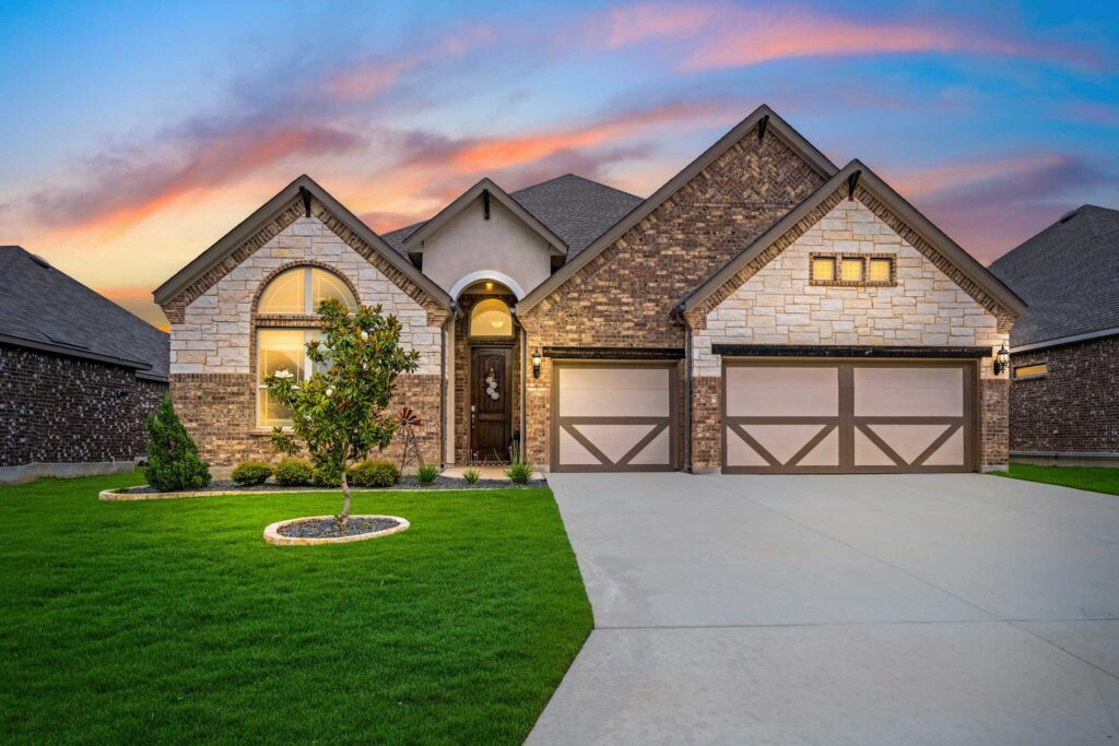AmCo Door Co. residential garage door installation on a brick home at sunset