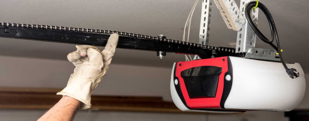 AmCo Door Co. technician installing a garage door opener with lifting mechanism and wiring
