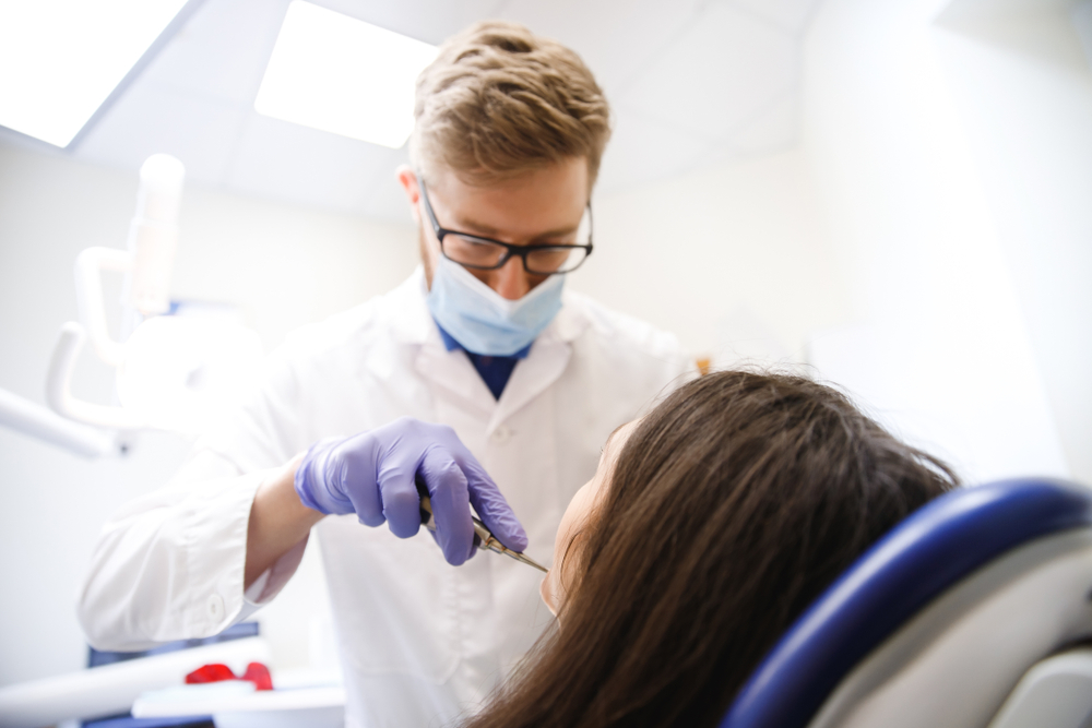 Pediatric dentist at Johnson Pediatric Dentistry examining a child in a dental chair with protective gear