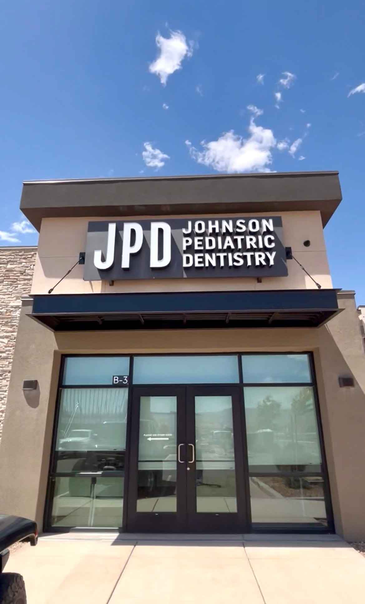Johnson Pediatric Dentistry building exterior sign against a blue sky with clouds