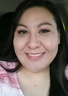 Portrait of a woman wearing glasses and a black outfit.