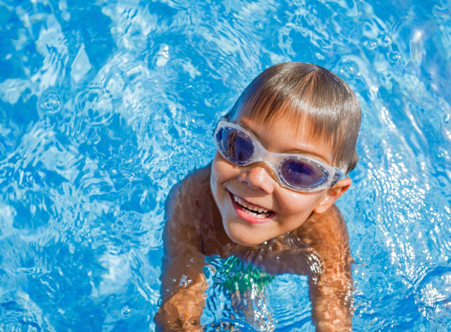 Happy little kid swimming in home pool on hot summer day