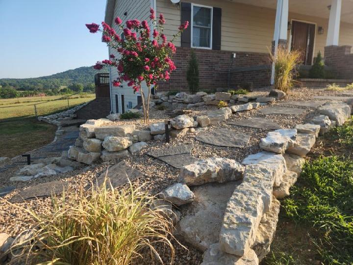 YardDawg Landscaping & Design stone retaining wall and landscaped garden with flowering tree near a home