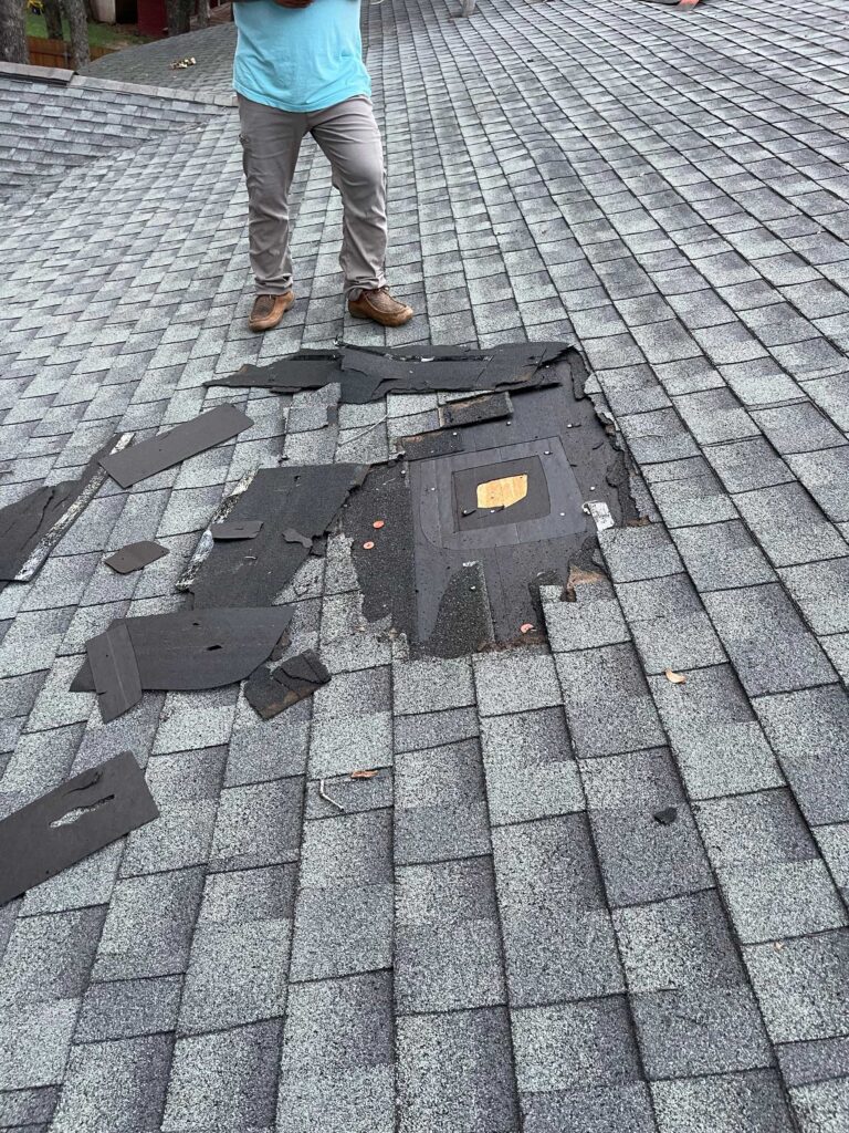 JN Roofing technician standing on damaged asphalt shingle roof during repair