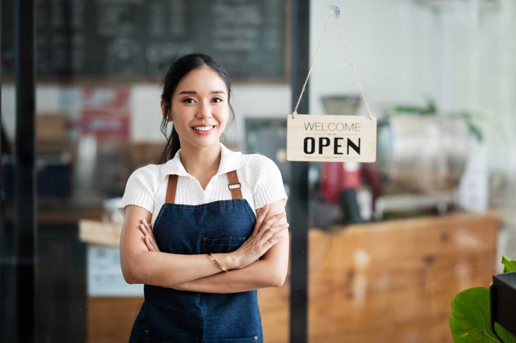 Cole Insurance Agency LLC agent smiling in front of a storefront with an OPEN sign