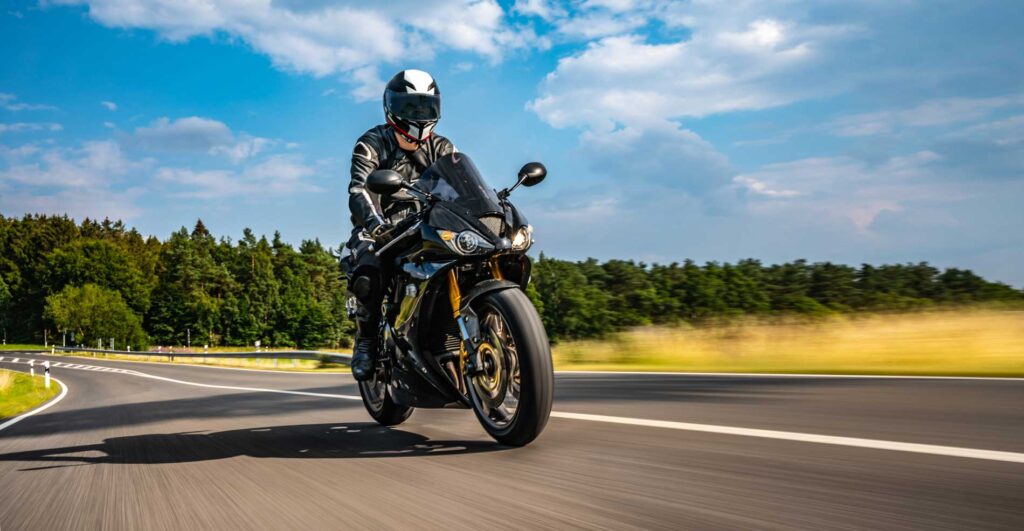 Motorcyclist riding on an open road under a blue sky
