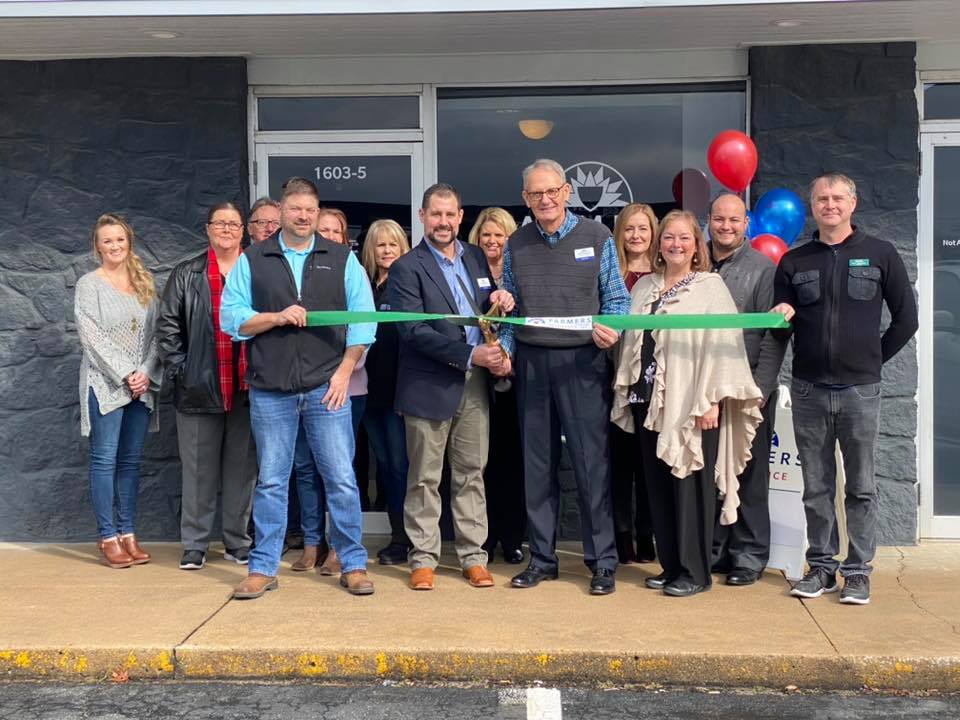 Cole Insurance Agency LLC team members cutting a ribbon in front of their office with balloons