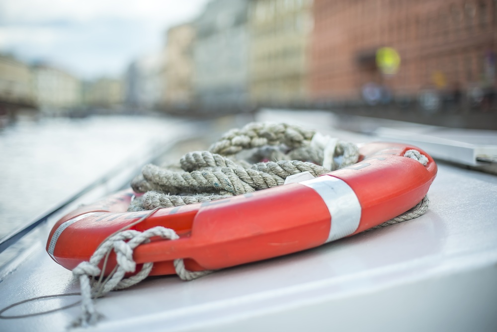 Life ring and rope on a boat with city buildings in the background for Cole Insurance Agency LLC