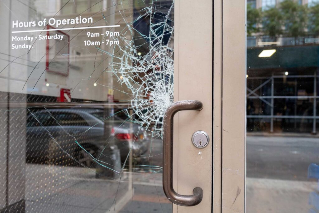 Mid Coast Glass storefront door with cracked safety glass showing business hours of operation