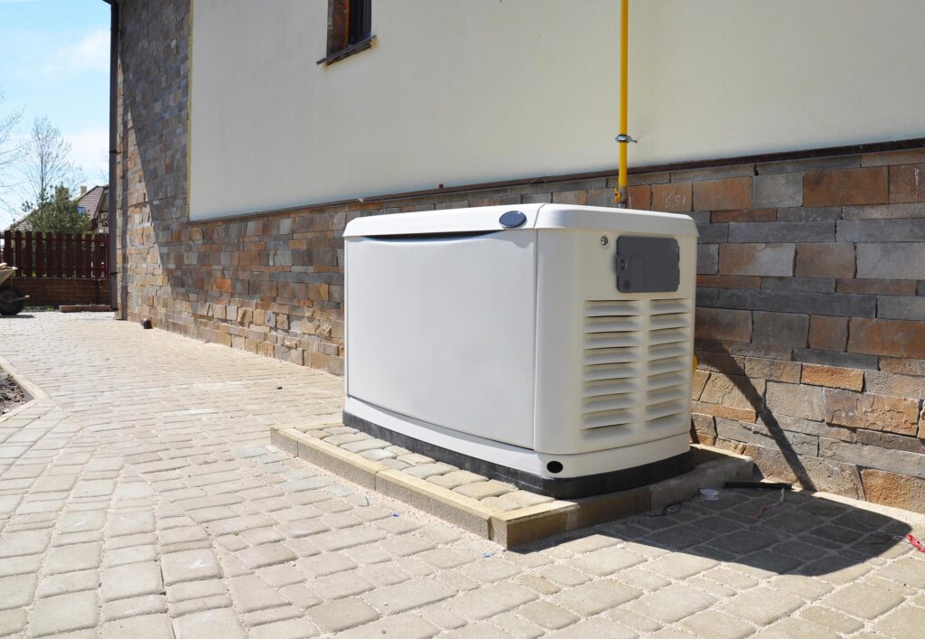 Barney Bros Electric Inc. outdoor electrical generator unit beside a stone wall