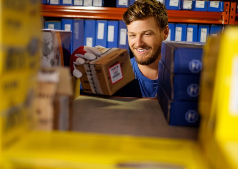 Denver City Motor Parts warehouse worker smiling while holding an auto parts delivery box