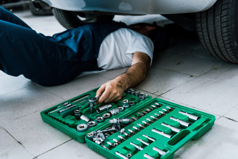 Technician working on a vehicle using a socket and wrench tool kit at Denver City Motor Parts