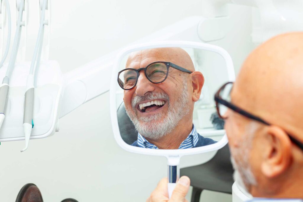 Digital dentures Kingston, reflection smiling man