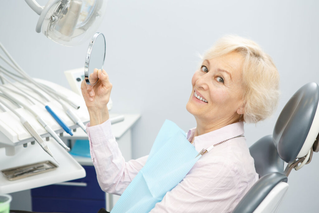 Denture reline Kingston, smiling woman, dentist chair, mirror reflection
