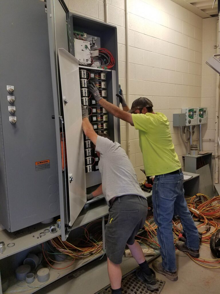 Electricians installing and wiring an electrical control panel inside a commercial facility for Marshall & Evans Electric Inc.