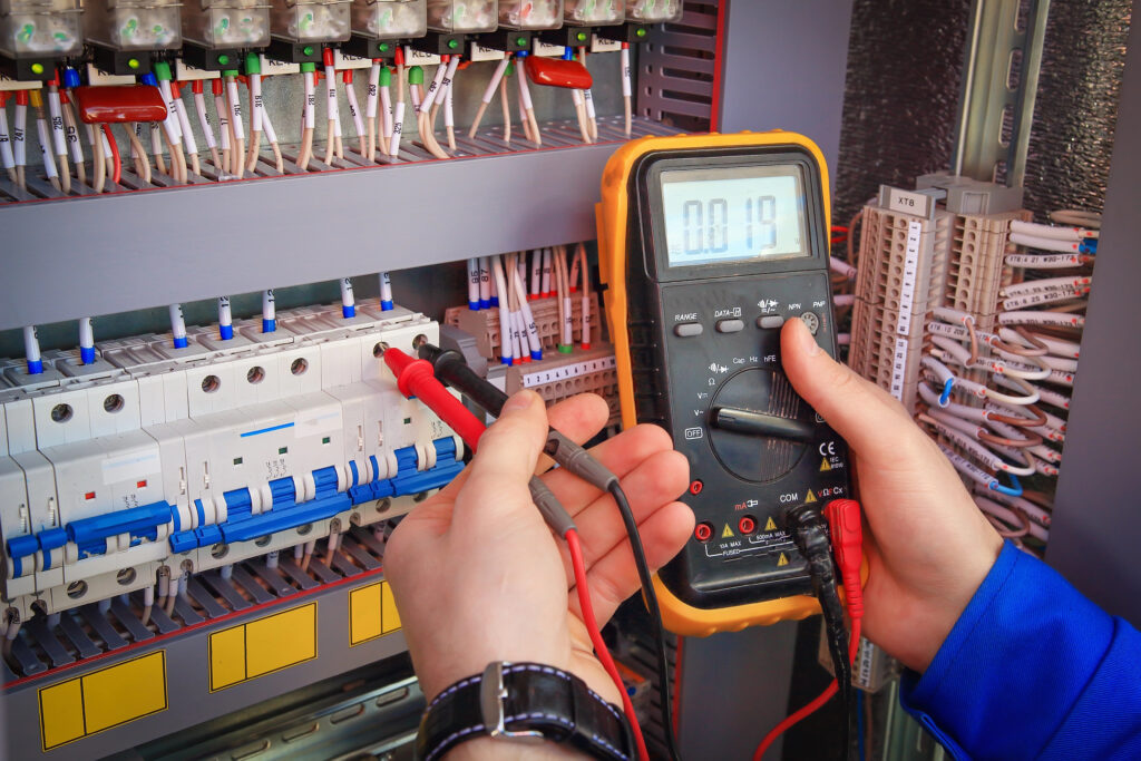 Electrician testing a circuit with a multimeter in an electrical panel at Marshall & Evans Electric Inc.