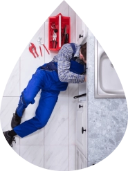 Technician from John G Plumbing Inc installing a plumbing fixture indoors