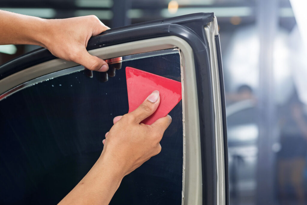 Technician applying window tint film to a car window