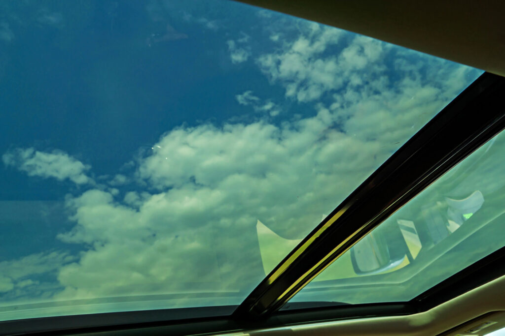 Mobile window tinting on car windshield reflecting clouds and sky