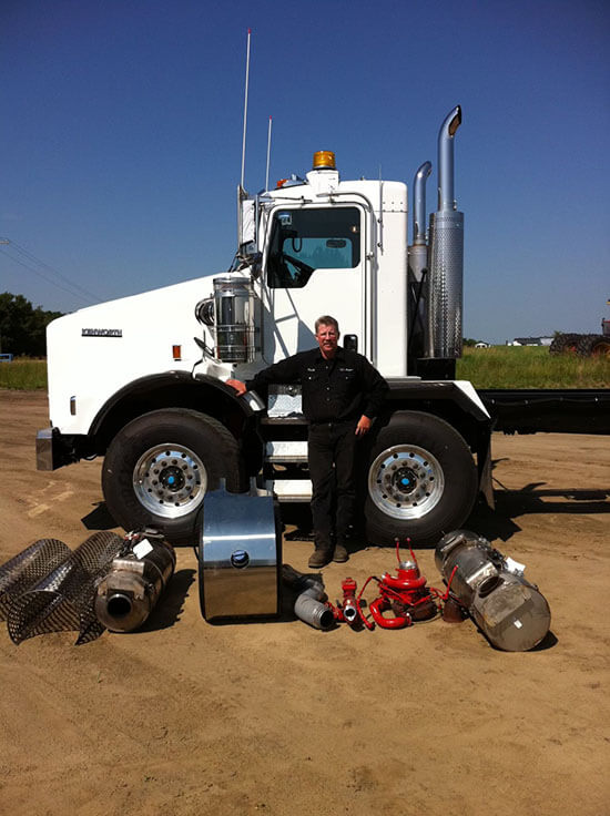 Technician from KJ's Repair Service Ltd standing beside a heavy-duty truck and repair equipment