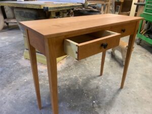 Handcrafted wooden desk with two drawers and CNC routing details in a workshop