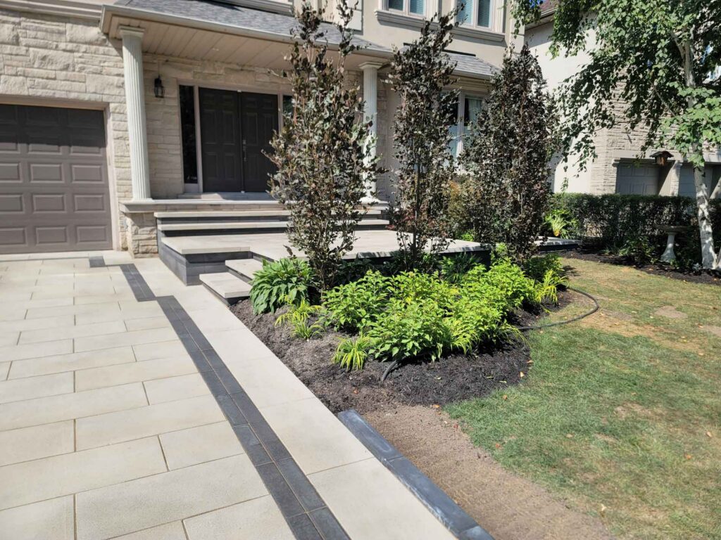 Northern Stone Design Inc. front walkway and landscaping with stone patio, benches, and garden beds
