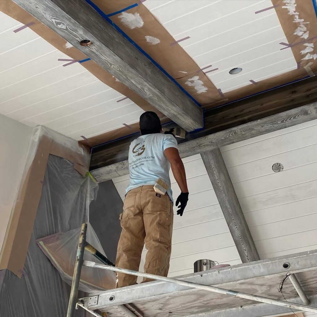 CB Paint & Decor painter applying paint on ceiling beams during interior decorating