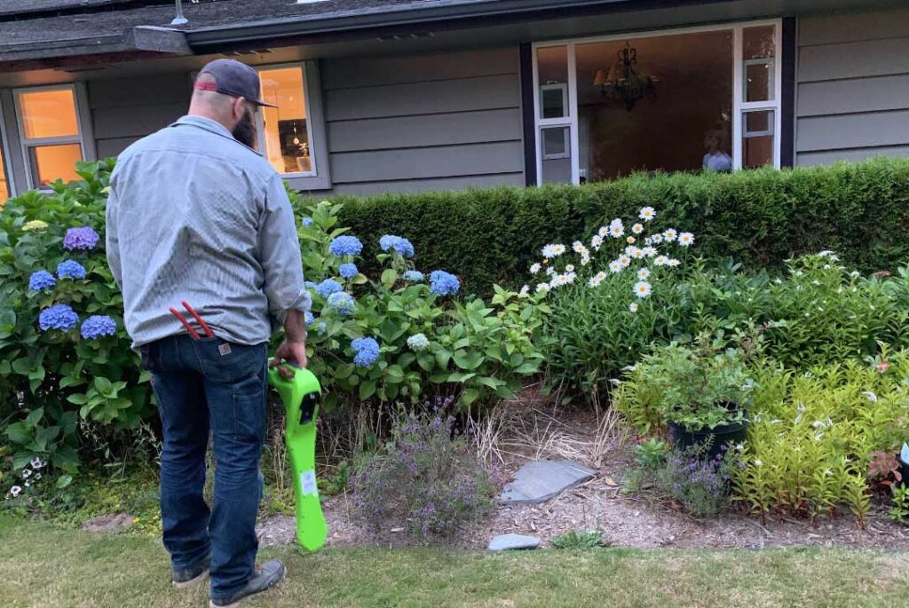 Skagit Sewer Specialists technician holding yard equipment in a landscaped front yard