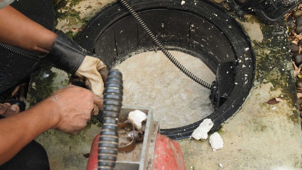 Skagit Sewer Specialists technician using sewer jet hose to clean a clogged drain