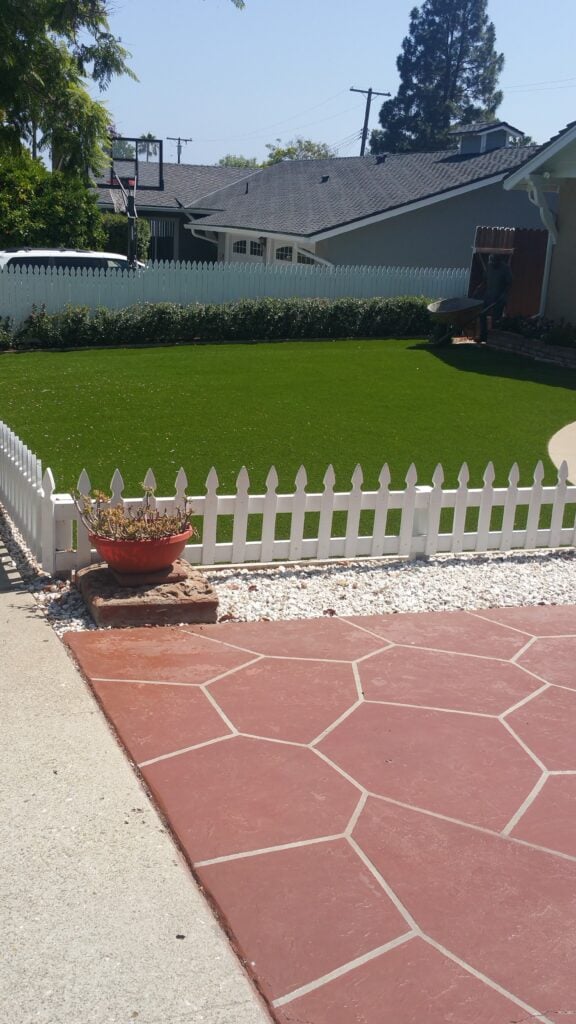 Casa Landscape Maintenance front yard lawn, white picket fence, and paver patio landscaping