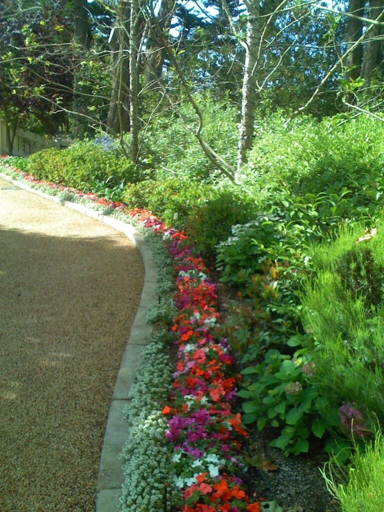 Casa Landscape Maintenance landscaped garden with colorful flower bed and pathway edging