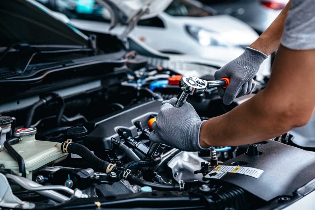 Gloved mechanic using a wrench to repair a car engine