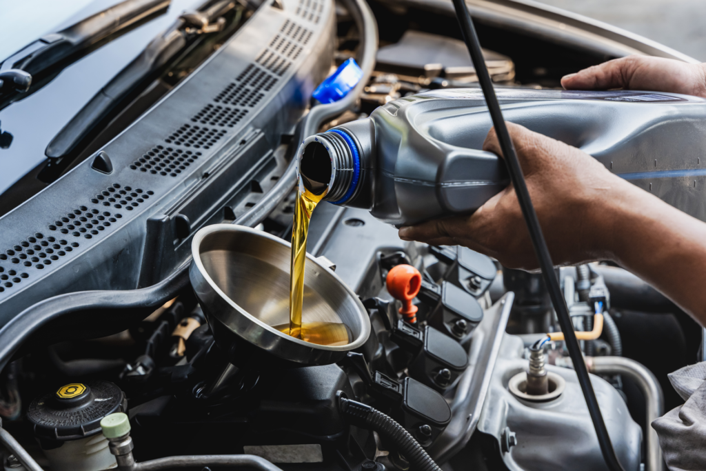 Hands pouring oil into a car engine using a funnel