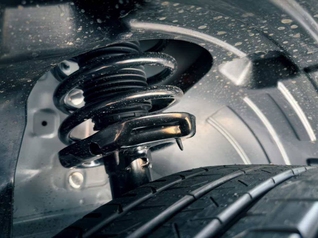 Close-up of a wet coil spring and strut assembly in a wheel well