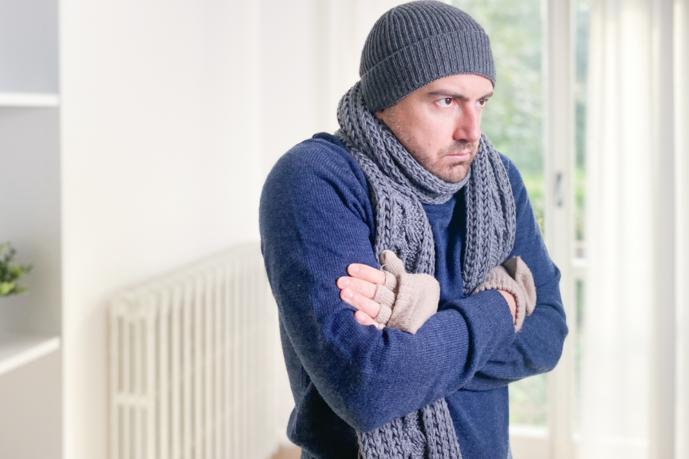 Man feeling cold at home with home heating trouble